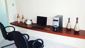 A reception desk with a computer, printer, and two decorative bottles. - Hotel Pio (Teresina)