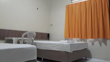 A hotel room with a bed, a chair, and an air conditioning unit.