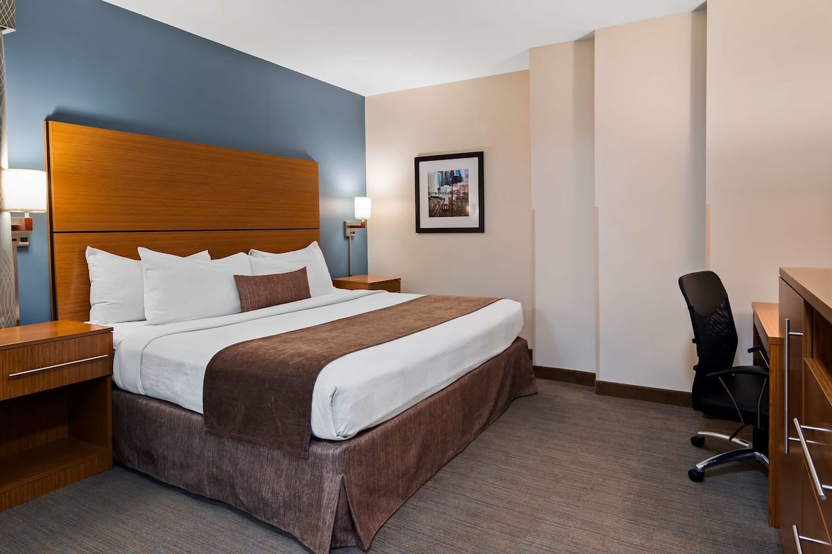 A hotel room with a large bed, a desk, a chair, and a television.
