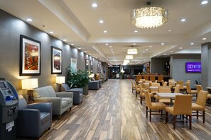 A hotel lobby with a long reception desk, seating area with sofas and chairs, and a wooden floor. - Best Western Plus Philadelphia Convention Center Hotel (Philadelphia)