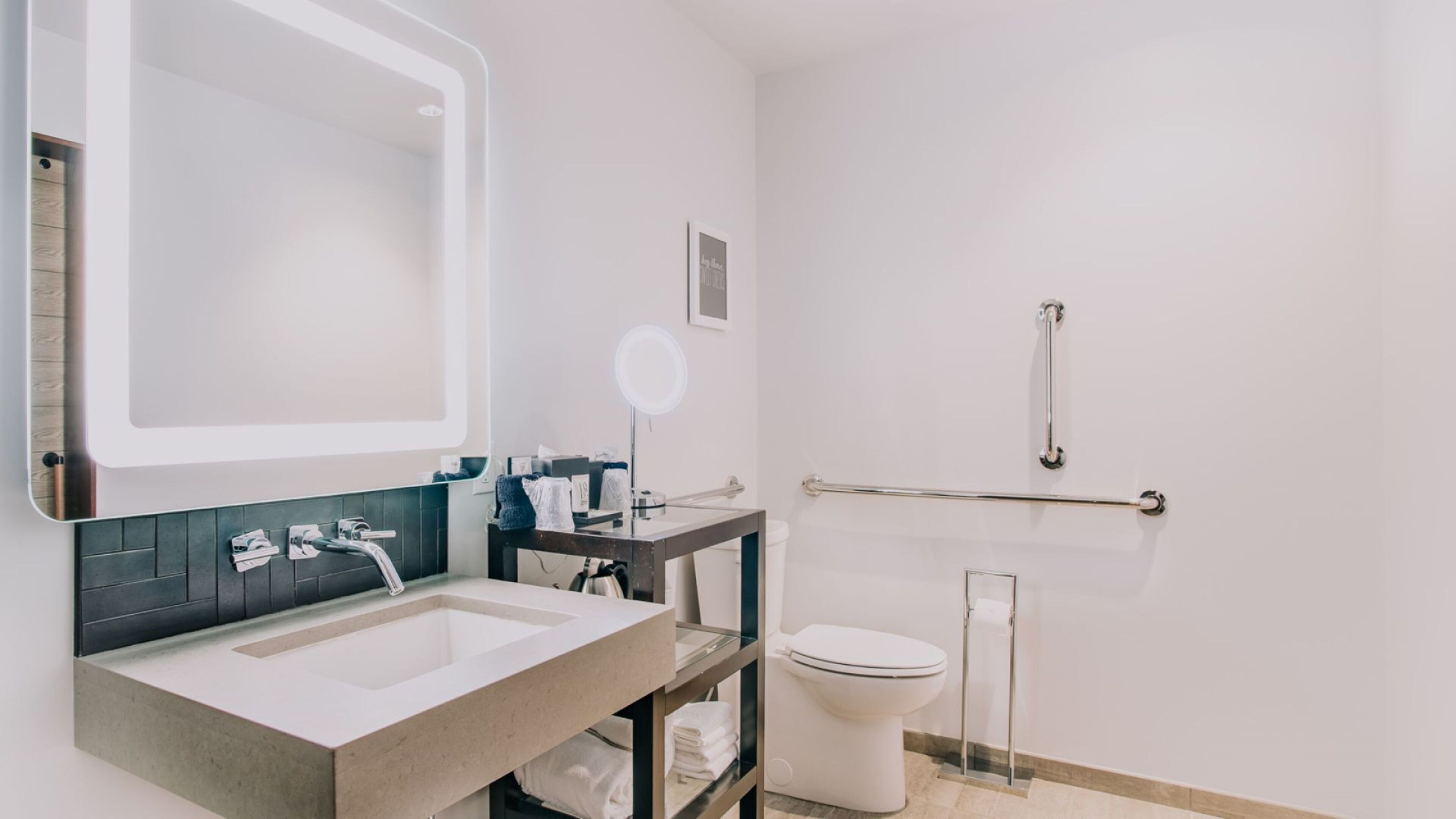 A modern bathroom with a large mirror, a sink, a toilet, and a shower area.
