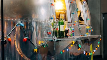A vintage train car with a bar area, decorated with colorful lights and bottles of alcohol.