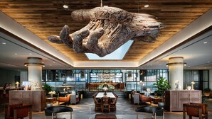 A spacious lobby with a large wooden ceiling sculpture, a central dining area, and modern furnishings. - The Maven Hotel at Dairy Block (Denver)