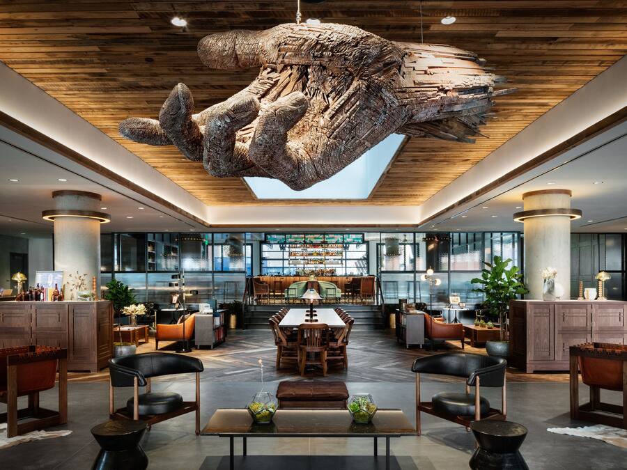 Un vestíbulo espacioso con una gran escultura de madera en el techo, una zona de comedor central y muebles modernos.