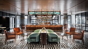 A bar area with a central bar counter, two sofas, and a patterned floor. - The Maven Hotel at Dairy Block (Denver)