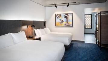 A hotel room with two beds, a wooden headboard, a painting on the wall, and a blue carpet.