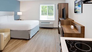 Une chambre d’hôtel avec un lit, un bureau, une télévision et une fenêtre avec des stores.