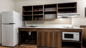 Une cuisine avec un réfrigérateur blanc, un four à micro-ondes, des armoires en bois et un évier.