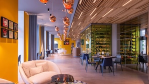 A modern restaurant interior with a central seating area, a bar, and a glass display case with shoes. - Golden Tulip Saint Malo - Le Grand Bé (Saint-Malo)