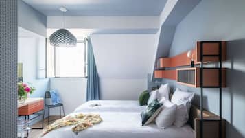 Un dormitorio moderno con una cama grande, un escritorio con silla, una lámpara colgante y una ventana con cortinas.