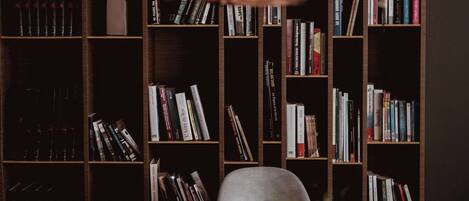 Una habitación con una estantería llena de libros, un sillón moderno y una mesita con una planta.
