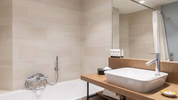 Une salle de bain moderne avec une baignoire sur pieds, un meuble-lavabo en bois doté d’un grand évier et un miroir au-dessus du meuble-lavabo.