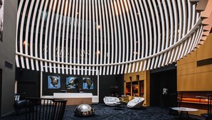 A modern lobby with a unique curved ceiling design, a reception desk, seating areas, and artwork on the walls. - Golden Tulip Saint Malo - Le Grand Bé (Saint-Malo)