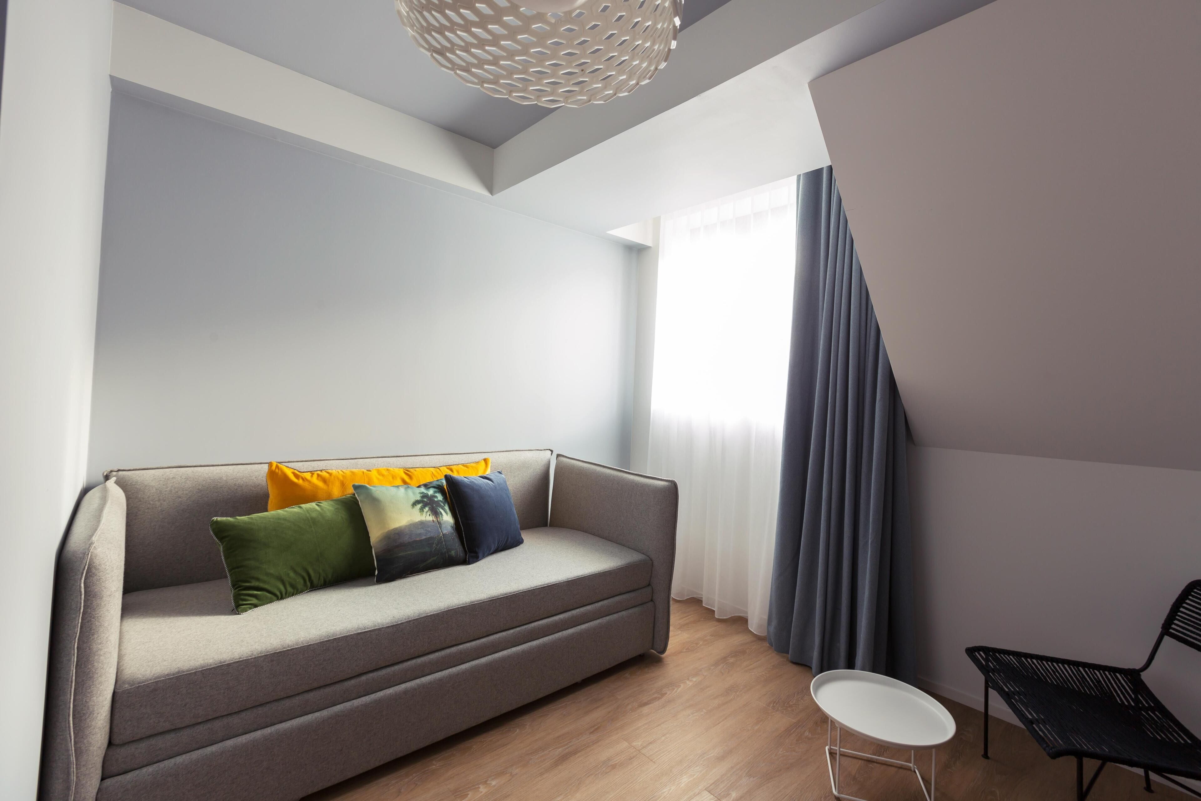 Een moderne woonkamer met een bank, een klein rond tafeltje en een stoel.