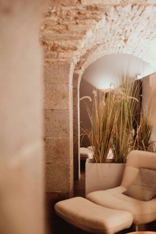 A cozy corner with a stone wall, a cushioned chair, and a potted plant.
