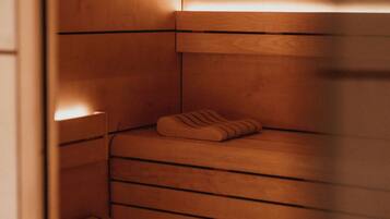 A sauna with wooden benches and a bench with a towel.