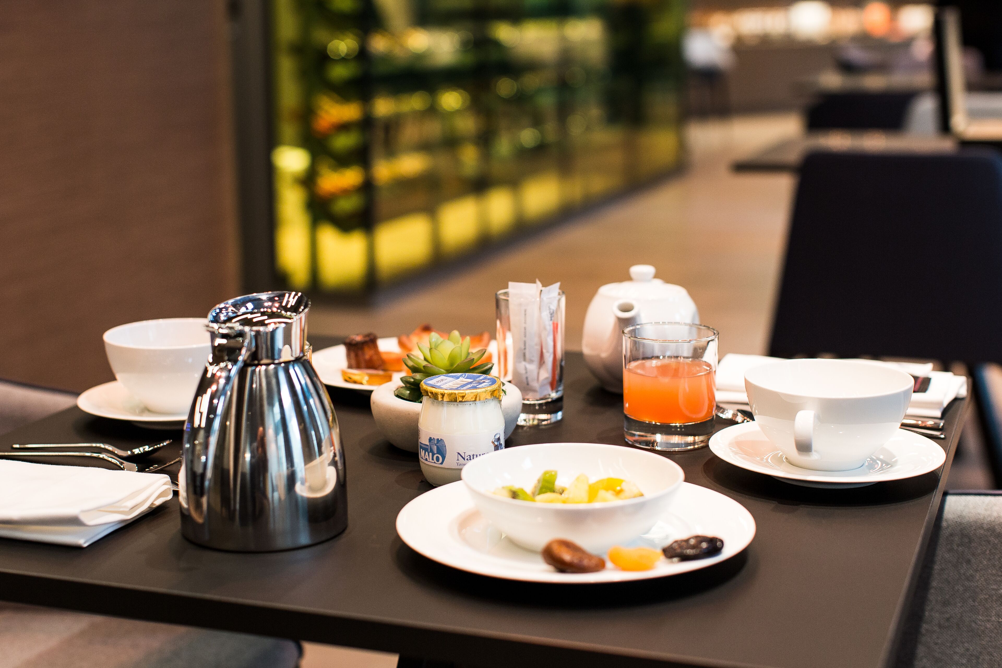 A breakfast table with a coffee pot, tea pot, juice, and various dishes.
