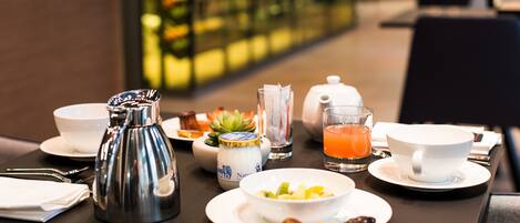 A breakfast table with a coffee pot, tea pot, juice, and various dishes.