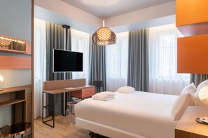 A modern hotel room with a large bed, a desk, a TV, and a unique hanging light fixture.