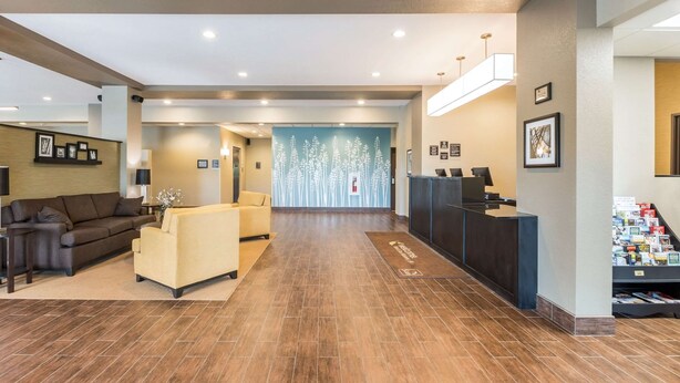 A hotel lobby with a reception desk, seating area, and a wall with a floral mural.