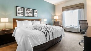 A hotel room with a large bed, two bedside tables with lamps, a chair, a desk, and a large window with curtains.