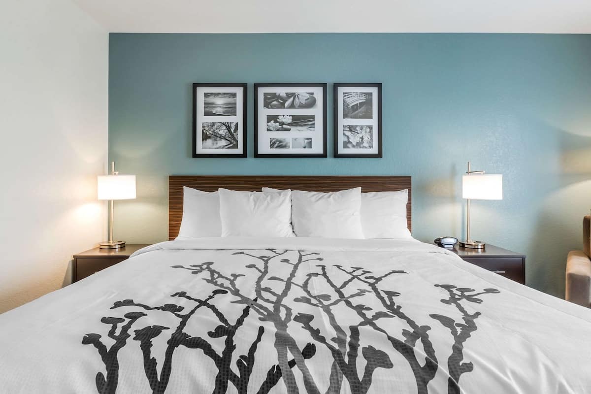 Ein Hotelzimmer mit einem Bett, zwei Nachttischlampen und drei gerahmten Bildern an der Wand.