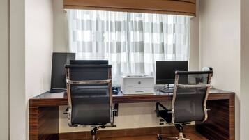 Un espacio de oficina moderno con dos sillas de oficina negras, un escritorio de madera, dos monitores e una impresora.
