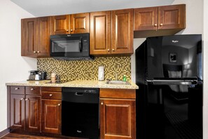 A kitchen with wooden cabinets, a black microwave, a black dishwasher, and a black refrigerator.