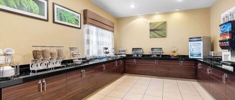 A modern kitchen with a black countertop, wooden cabinets, and a large window with blinds.