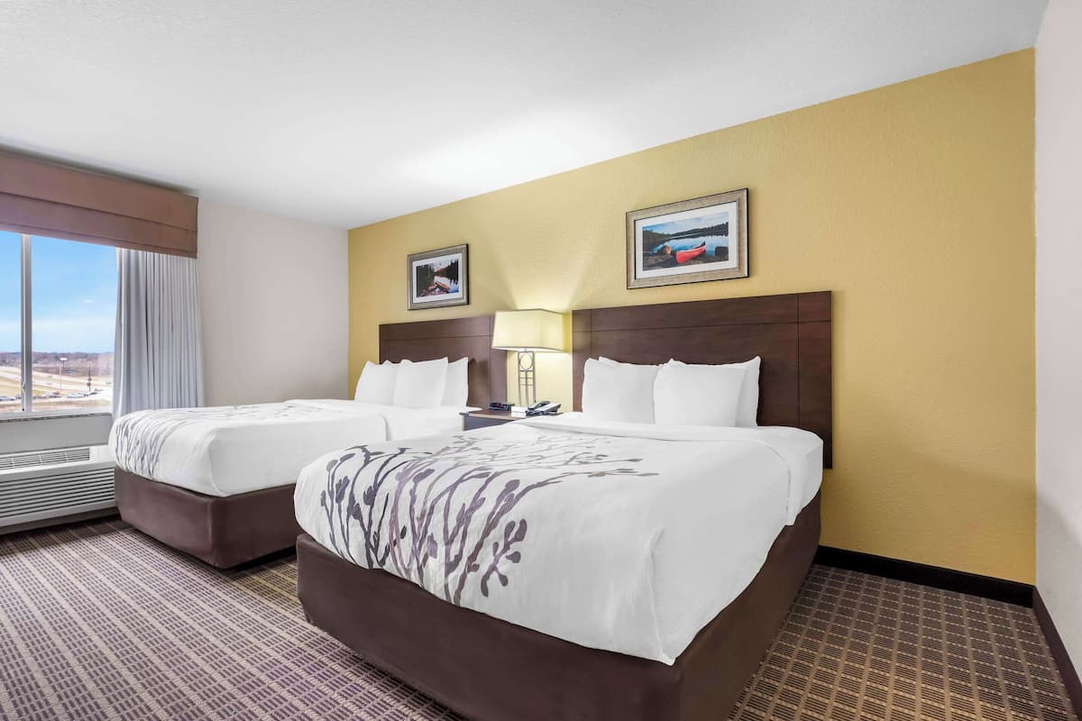 A hotel room with two beds, a large window, and a view of the cityscape.