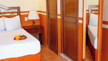 A hotel room with a bed, a nightstand, a lamp, a mirror, and a ceiling fan.