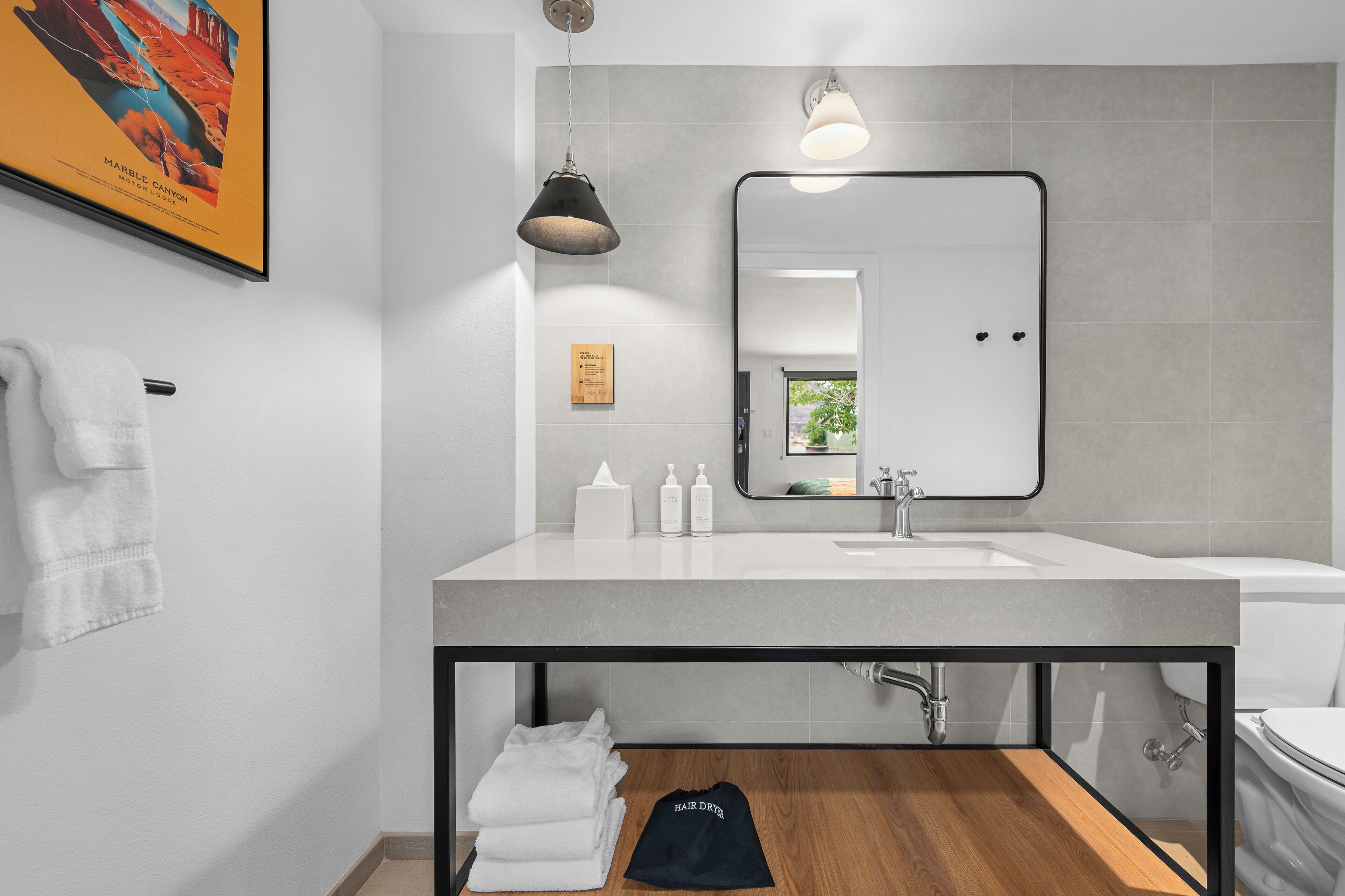 A modern bathroom with a large mirror, white sink, and a towel rack.