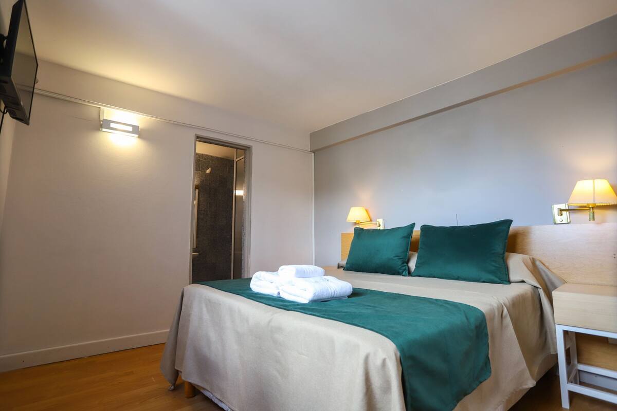 Ein Hotelzimmer mit Bett, Schreibtisch, Stuhl, Fernseher und Tür.