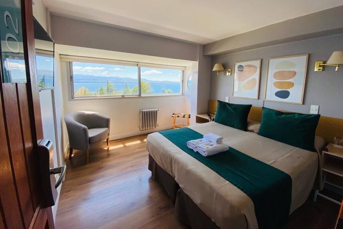 Ein Hotelzimmer mit einem großen Bett, einem Sessel, Meerblick und einer Heizung.