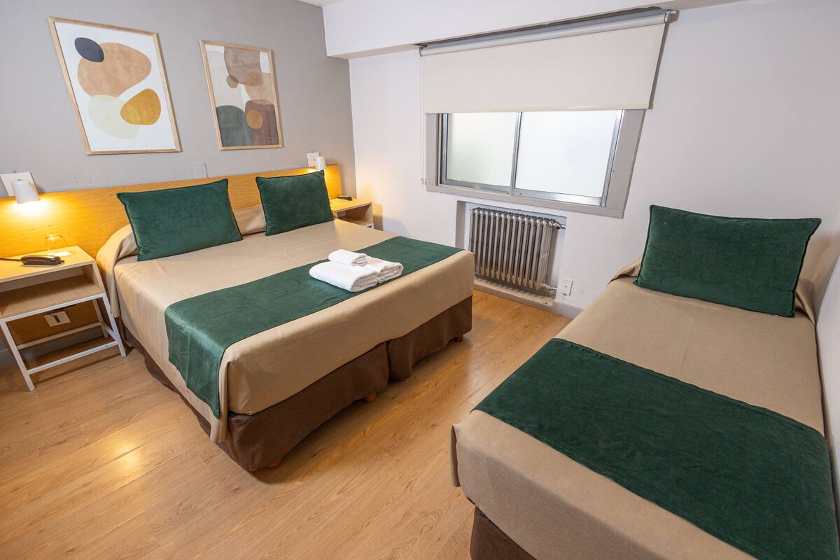 Ein Hotelzimmer mit zwei Betten, Holzboden, Heizkörper und Bildern an den Wänden.