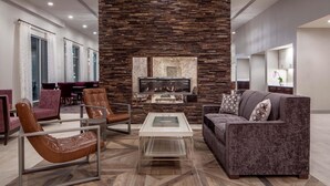 A modern living room with a stone fireplace, leather chairs, a sofa, and a television.