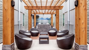 A covered patio with wicker furniture, a stone table, and a view of the backyard.