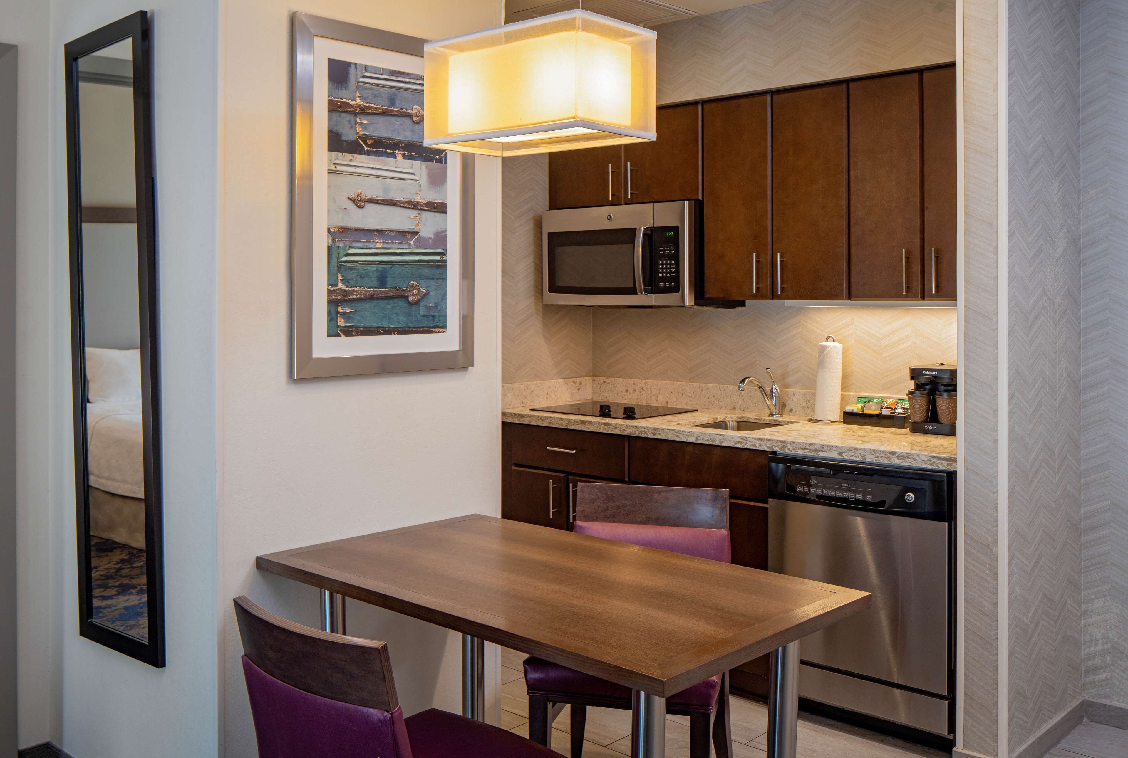 A compact kitchen with a microwave, dishwasher, and wooden cabinets.