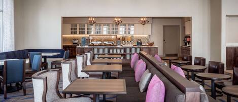 Un restaurant avec des banquettes et des tables, un coin bar et une cuisine située à l’arrière.