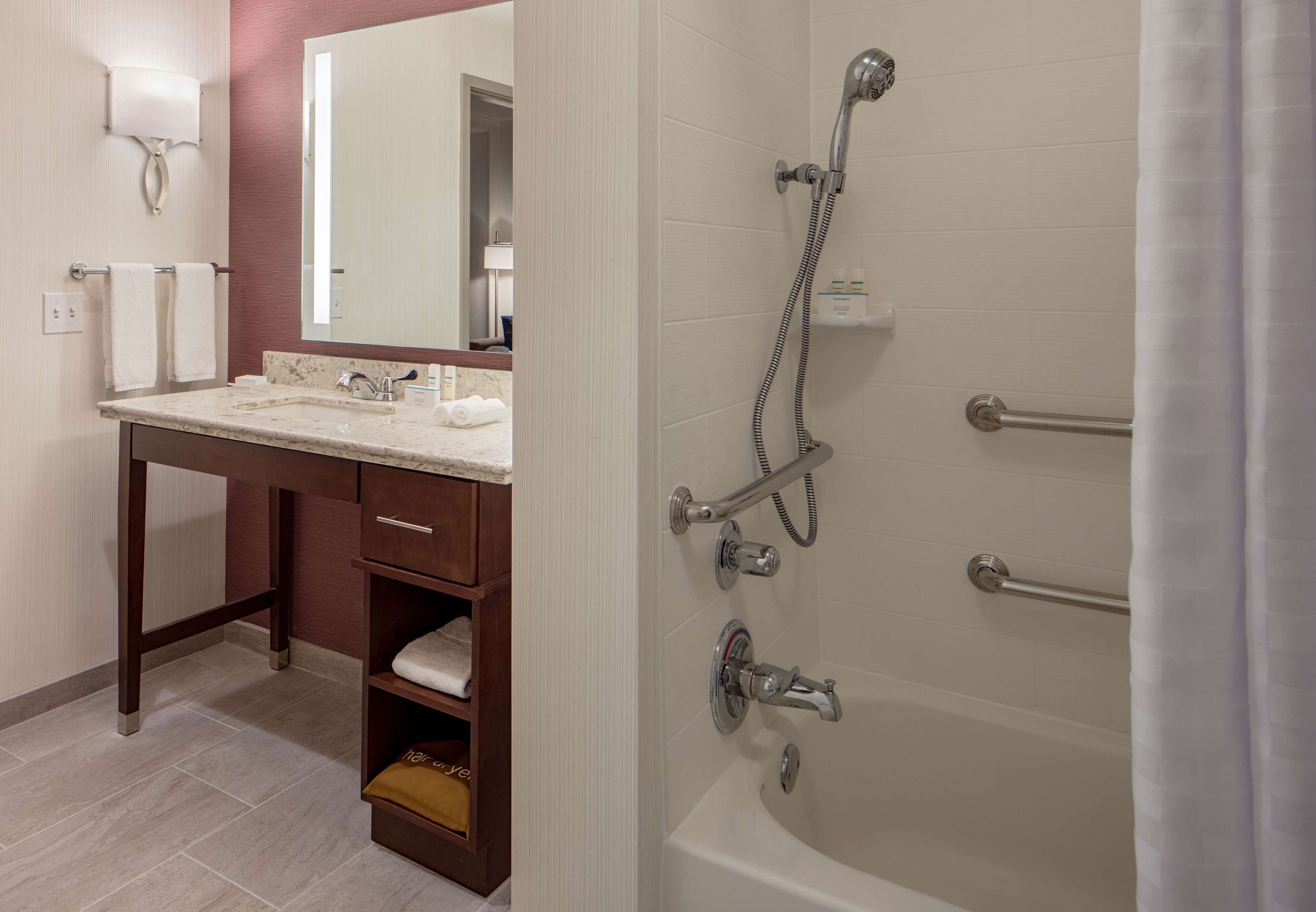 Un baño moderno con bañera, tocador con espejo y barra para toallas.