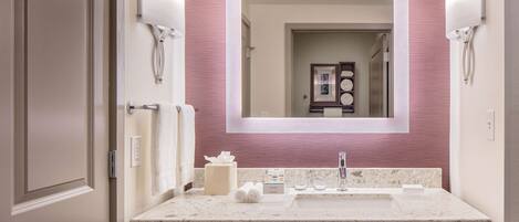 A bathroom with a marble sink, two towel dispensers, a mirror, and a door.