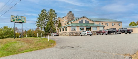 A Gateway Inn with a stone facade, a green roof, and a parking lot with several cars.