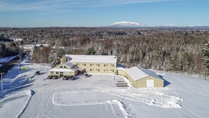 A large building with a snow-covered parking lot and a road leading to a 'Gateway' sign. - Gateway Inn (Medway)