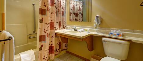 A bathroom with a shower, toilet, sink, and a mirror.