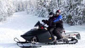 A snowmobile on a snowy path with trees on either side.