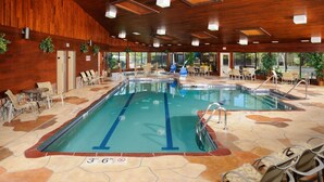 An indoor swimming pool with clear lane markings, surrounded by lounge chairs and tables. - The Pointe Hotel and Suites (Minocqua)