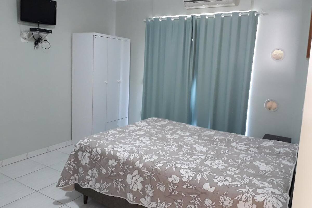 Une chambre à coucher comprenant un lit, une armoire, un téléviseur fixé au mur et un appareil de climatisation.