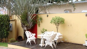 A patio with white ornate furniture, a small tree, and a red door. - Paradise Hotel (Campo Grande)