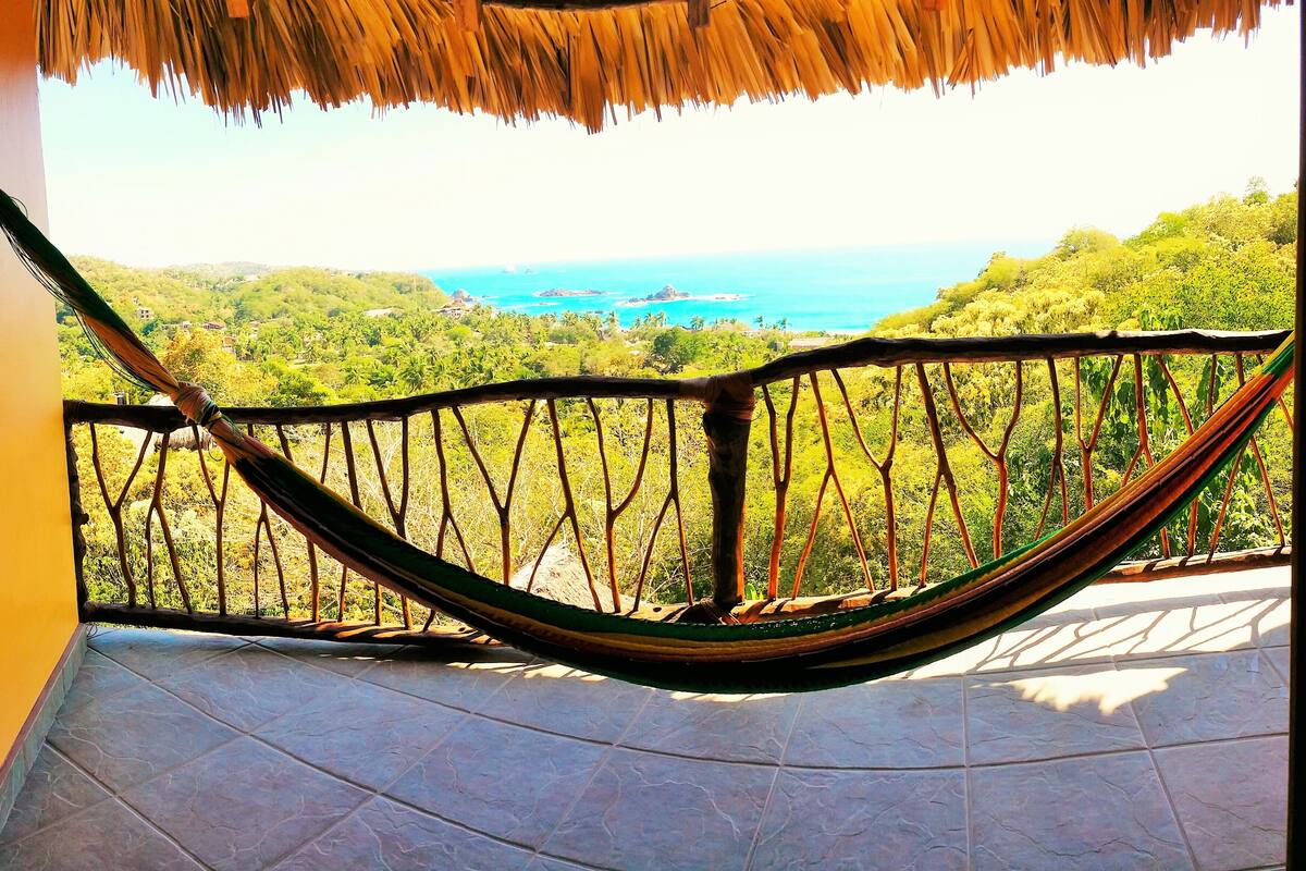 Un hamac sur un balcon donnant sur un paysage côtier.