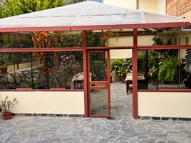 A conservatory with a glass enclosure, stone flooring, and potted plants.